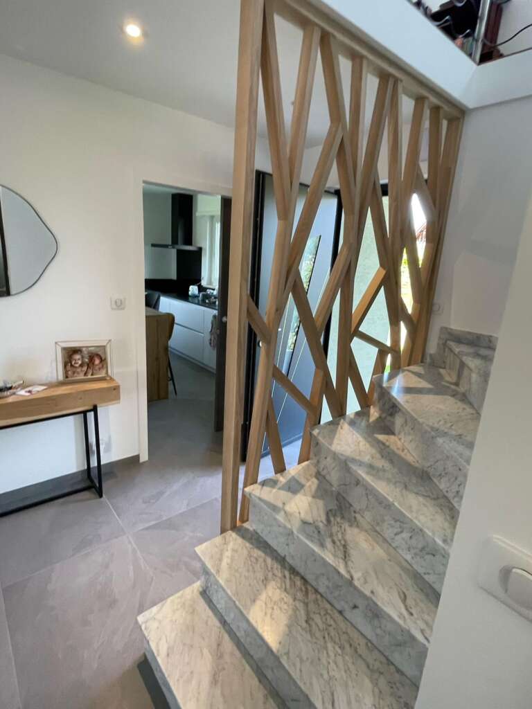 Garde-corps en bois à motif géométrique, vu depuis le bas de l’escalier