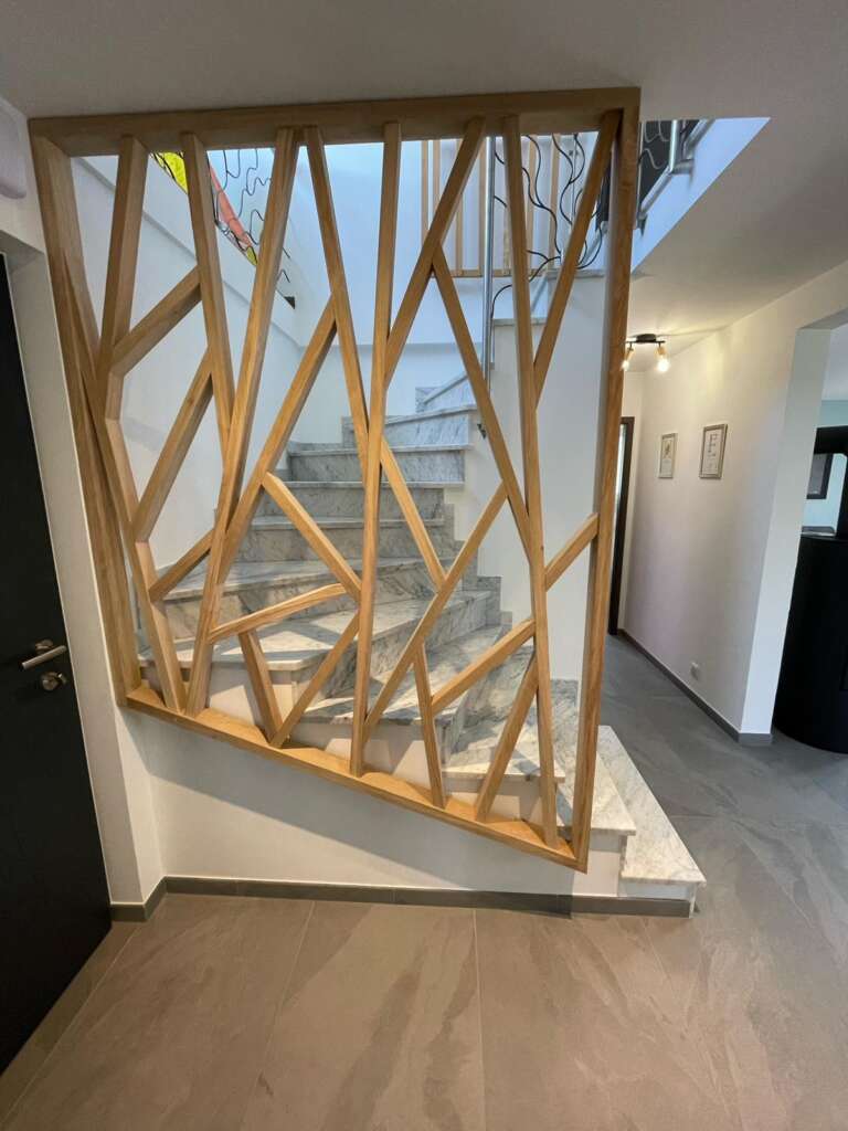 Garde-corps en bois à motif géométrique le long d’un escalier en pierre